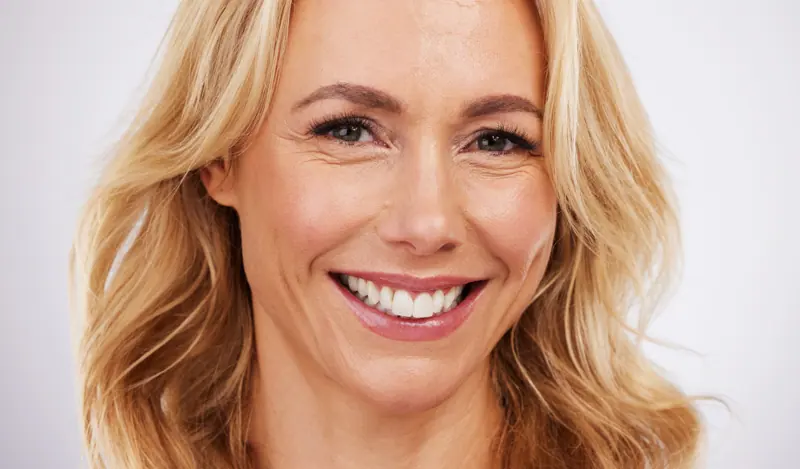 Blonde woman smiling with a white background