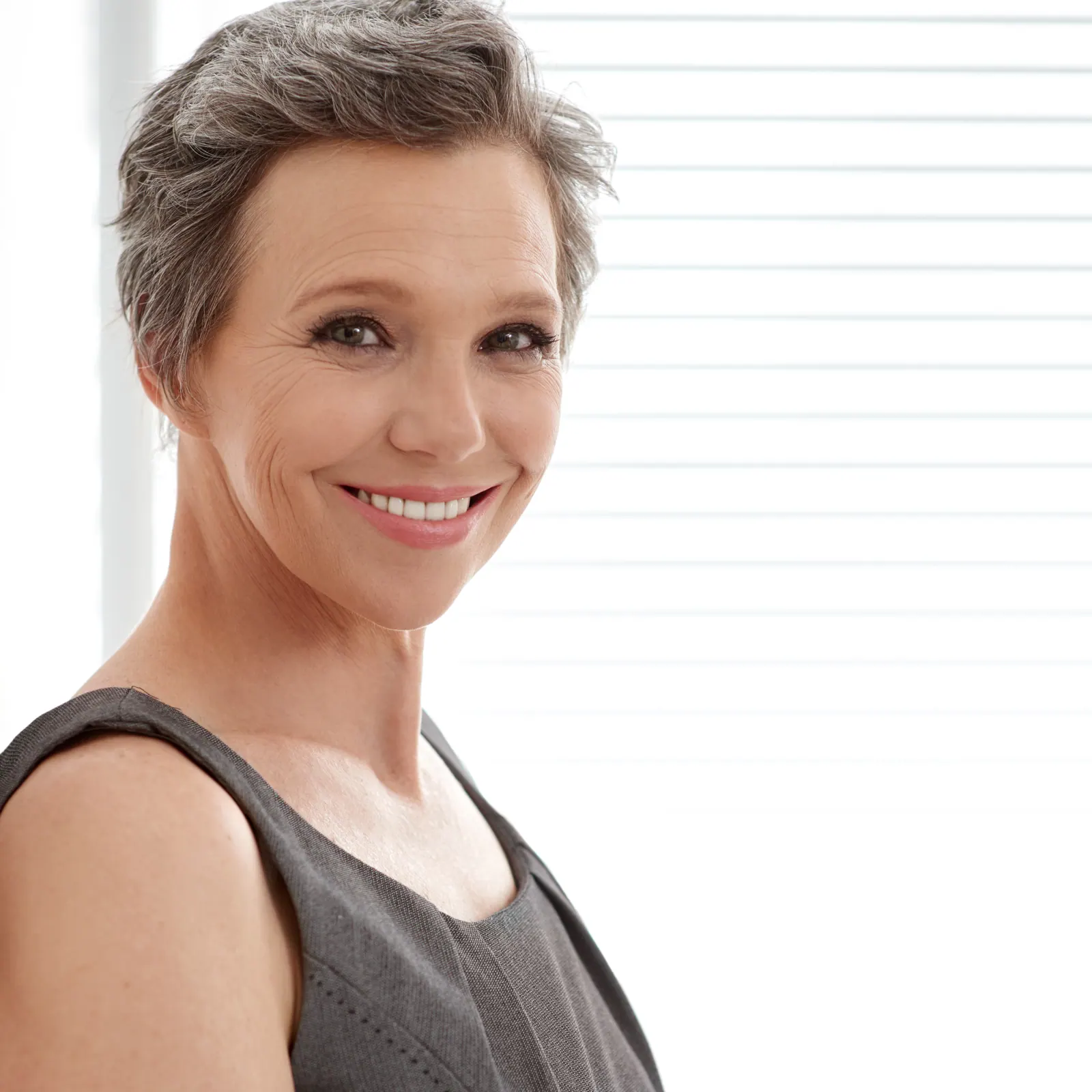 Elegant woman smiling with short grey hair indoors