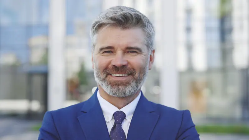 Gray haired man smiling close up in blue suit