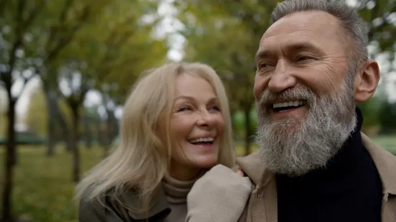 Happy couple laughing together in autumn park