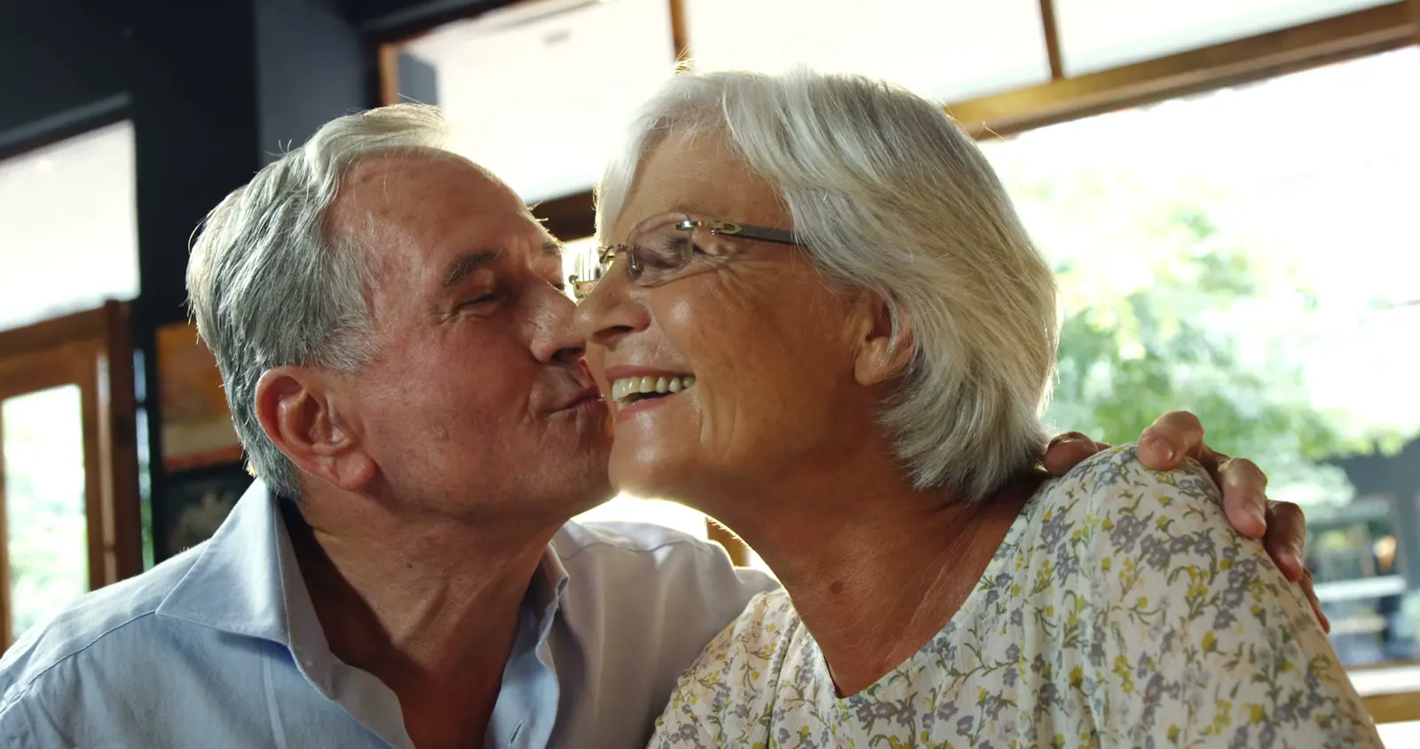 Happy senior couple kissing in the sunlight