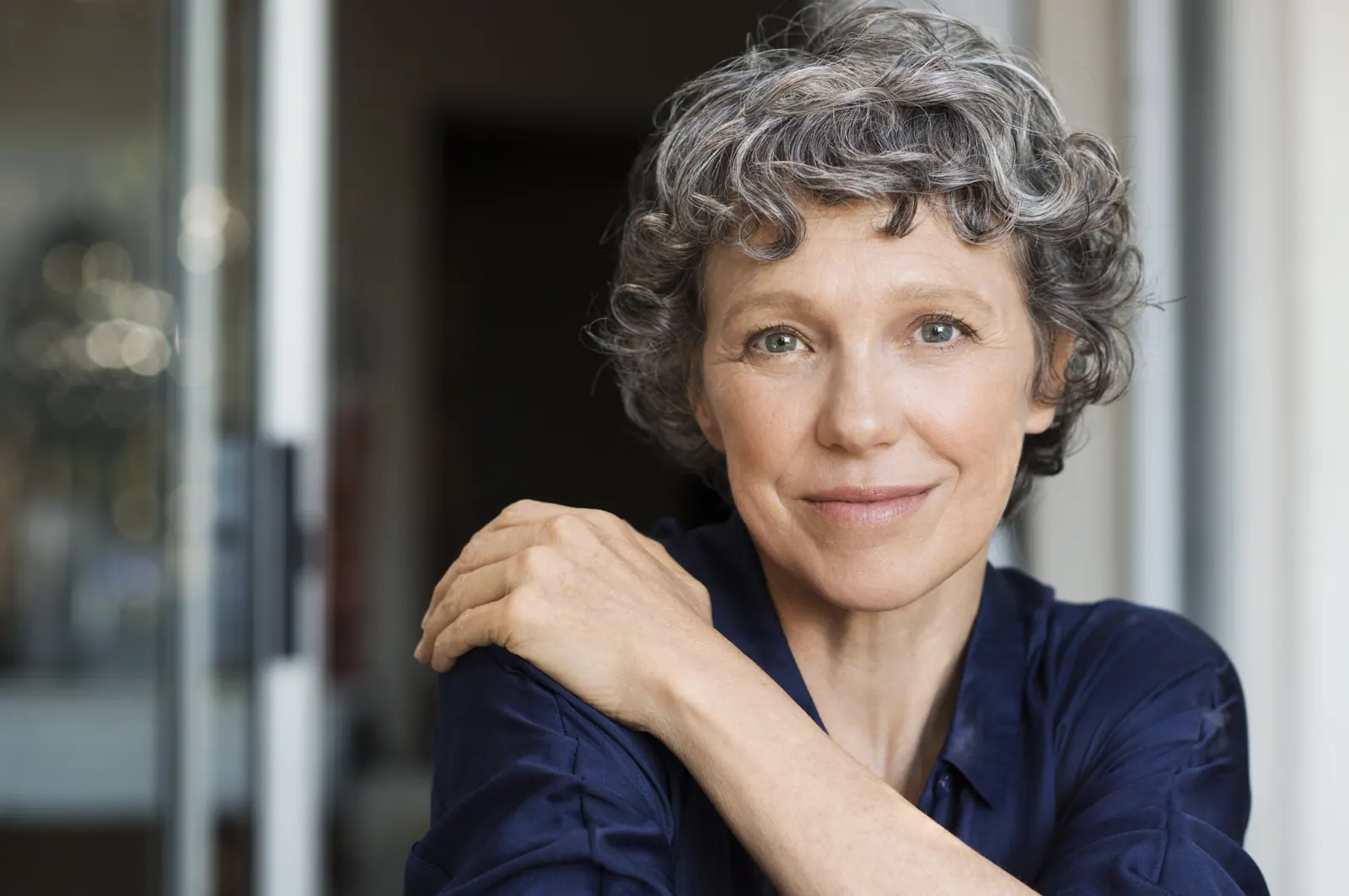 Mature woman with curly gray hair posing in doorwa