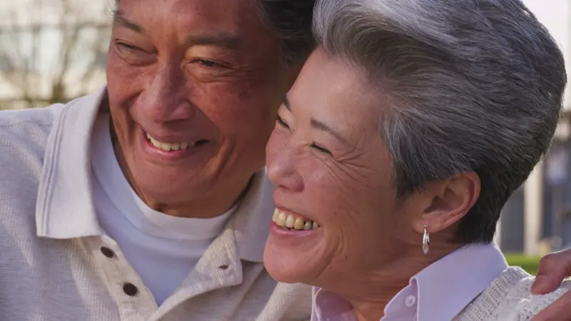 Senior couple embrace and smile together outdoors