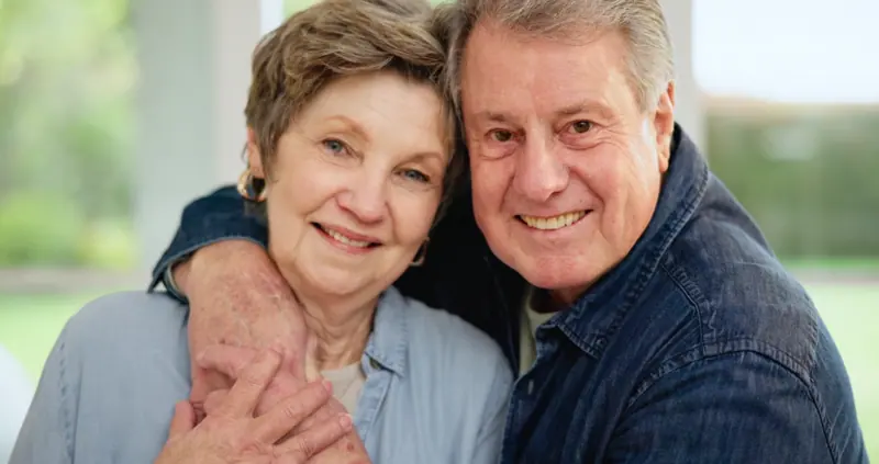 Senior couple embracing in sunny home setting