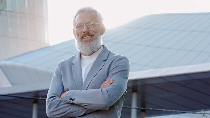 Senior man smiling confidently outside modern buil