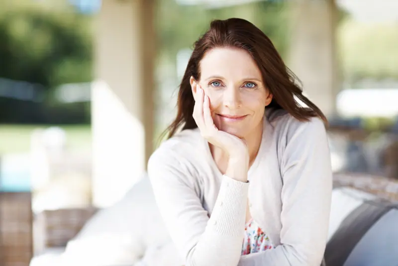 Serene woman relaxing on patio with calm smile