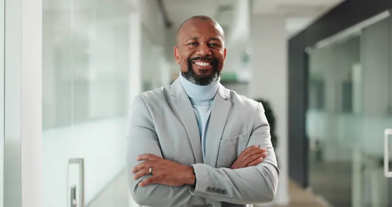 Smiling man in modern office with arms crossed