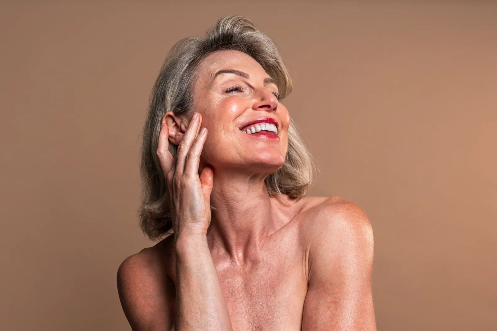 Smiling mature woman posing with hand on face