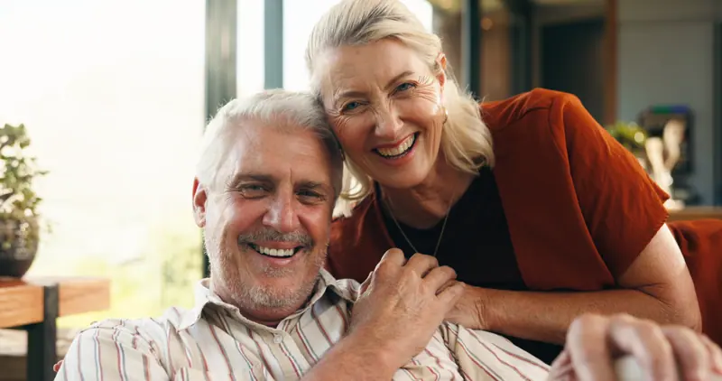 Smiling senior couple posing closely together indo
