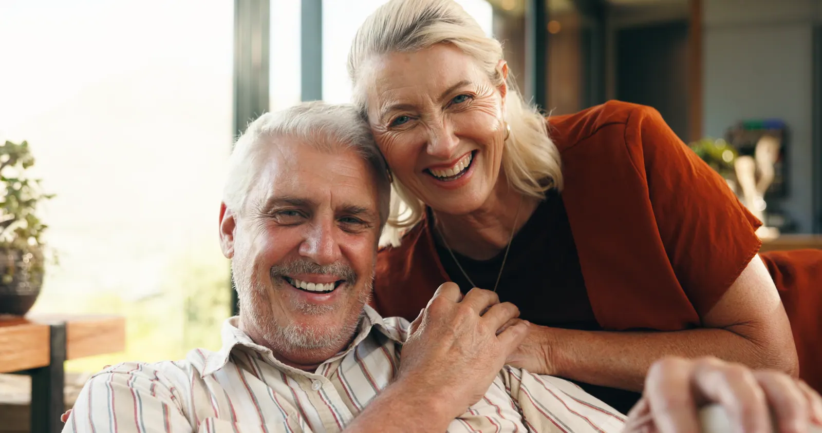 Smiling senior couple posing closely together indo