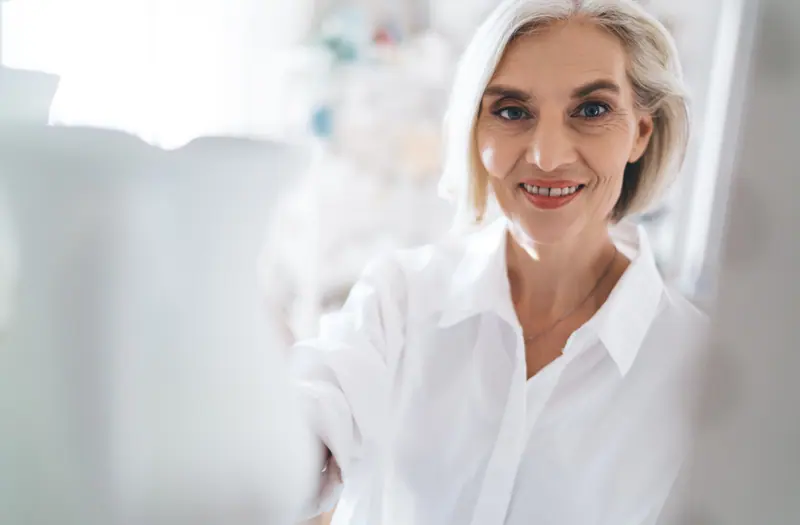 Smiling senior woman in white shirt indoors