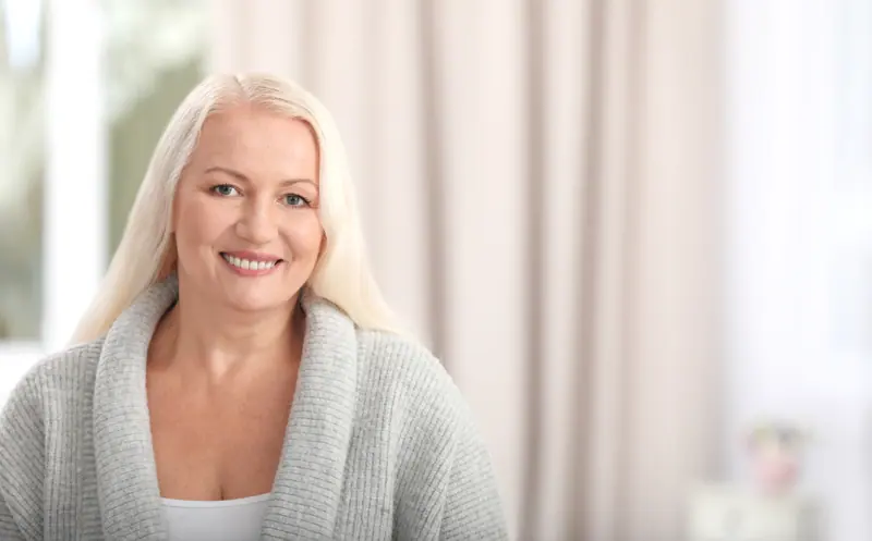 Smiling woman in a gray cardigan indoors