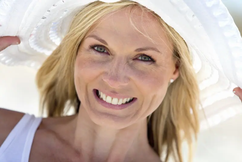 Smiling woman with blonde hair wearing a white hat
