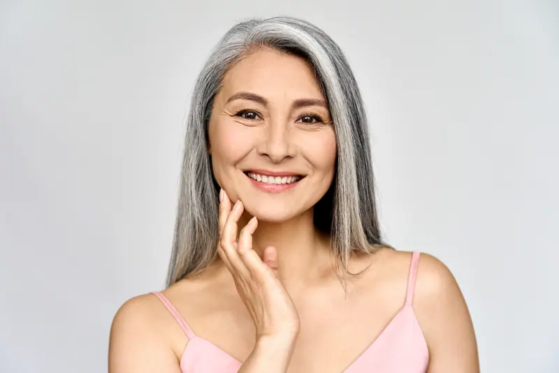 Smiling woman with gray hair posing in studio