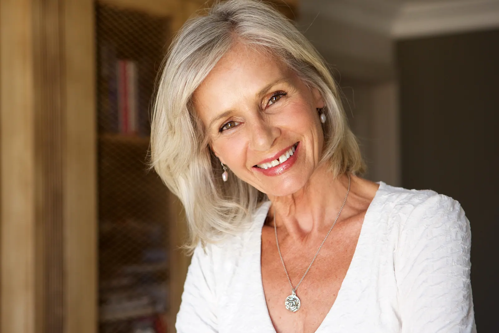 Smiling woman with gray hair wearing white indoors