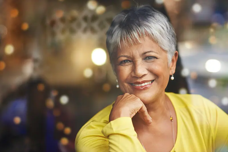 Smiling woman with grey hair posing indoors