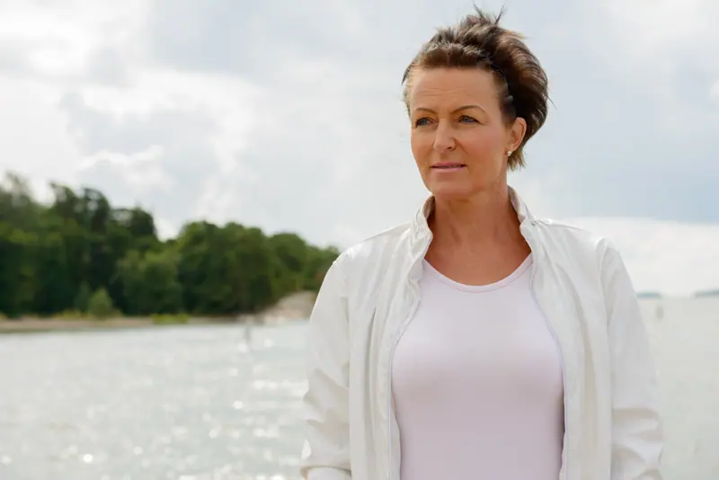Woman in jacket enjoys serene waterside vista