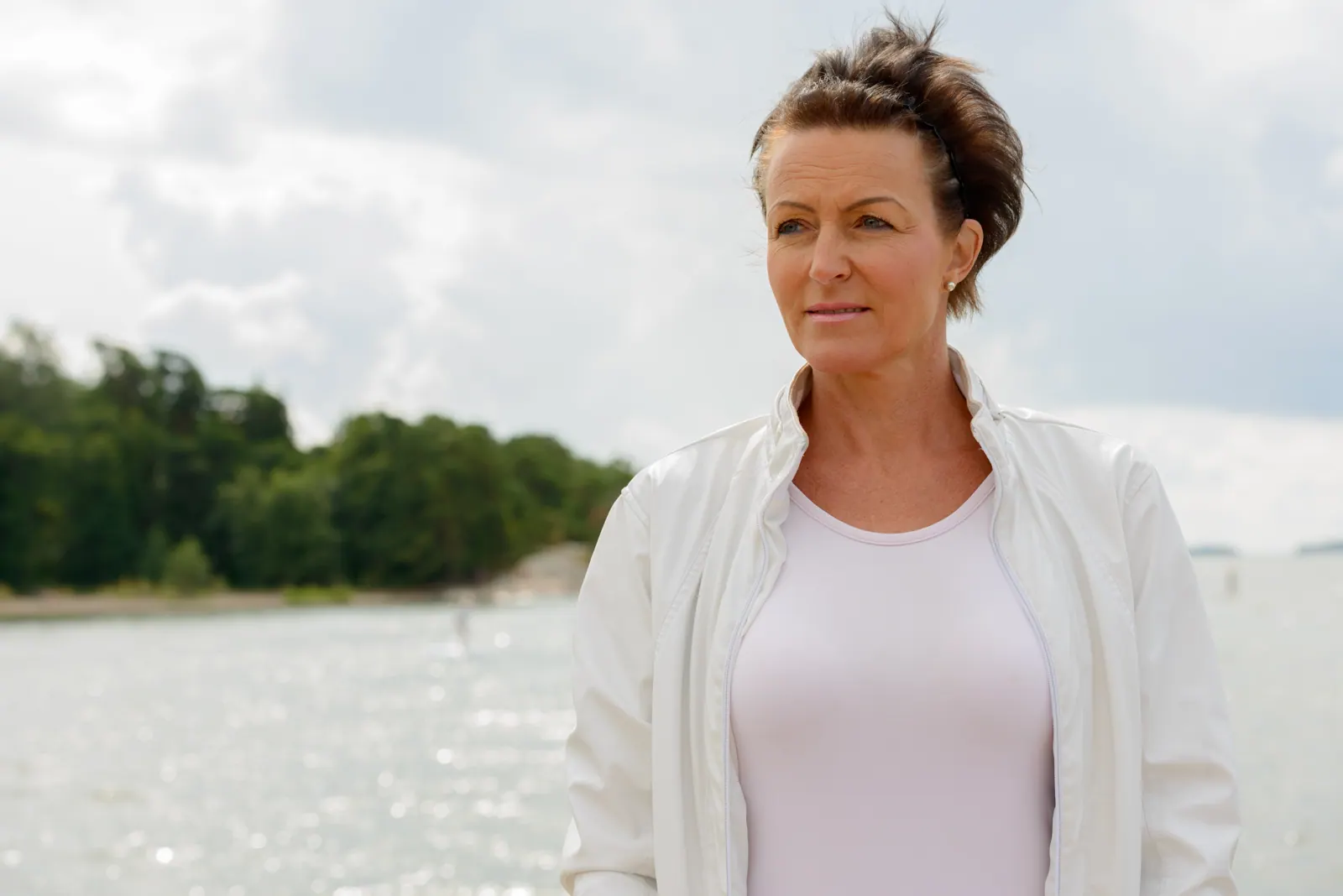 Woman in jacket enjoys serene waterside vista