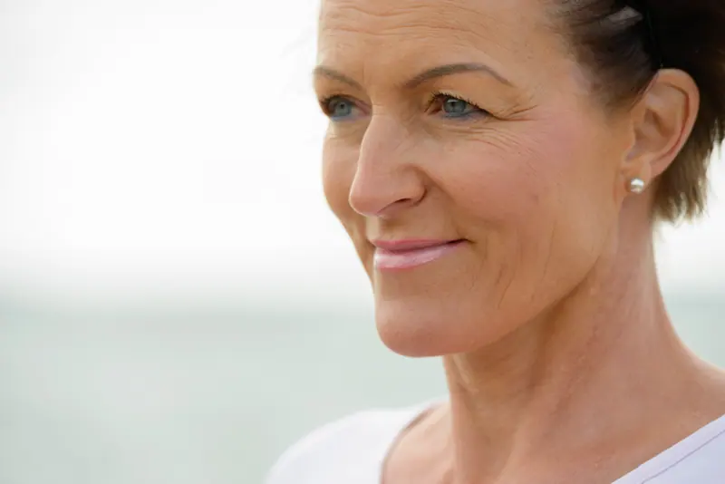 Woman smiles outdoors near a beach