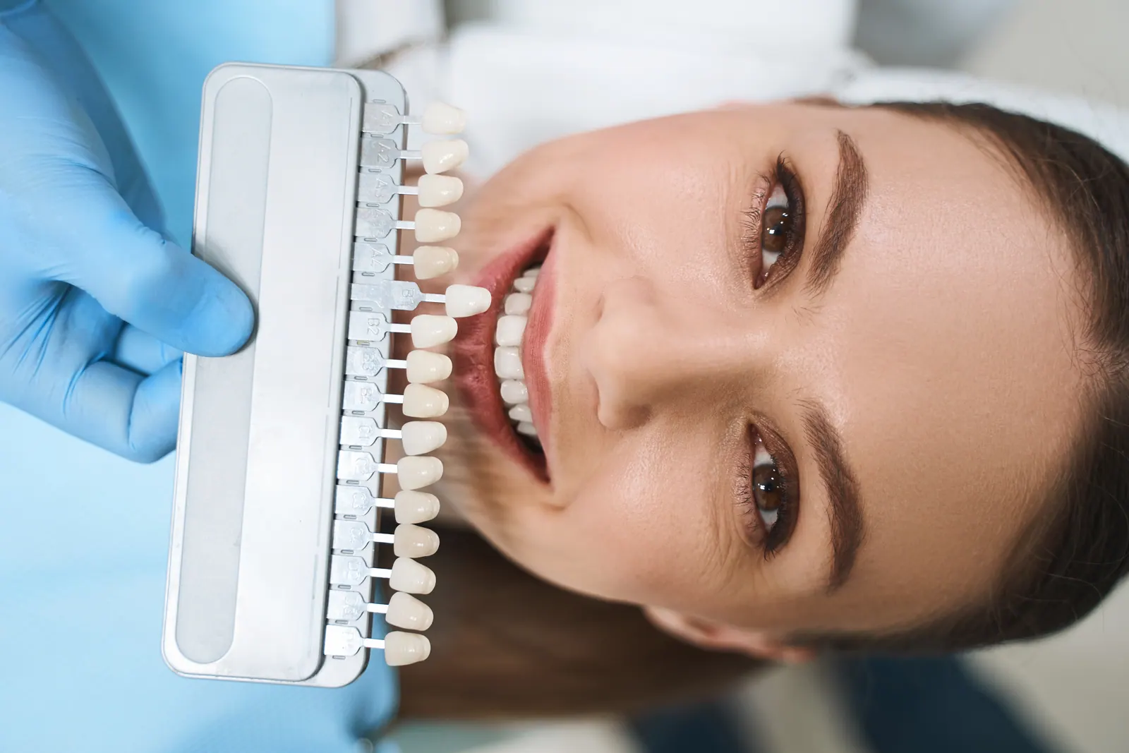 Woman smiling with tooth color chart in clinic